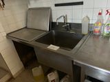 a stainless steel sink in a kitchen with a lot of cleaning supplies