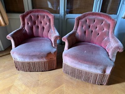 une paire de fauteuils recouverts de velours rose devant une fenêtre