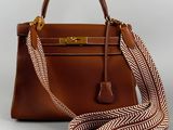 a brown leather handbag with a brown and white striped strap