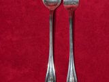 deux cuillères en argent et une fourchette posées sur une nappe rouge