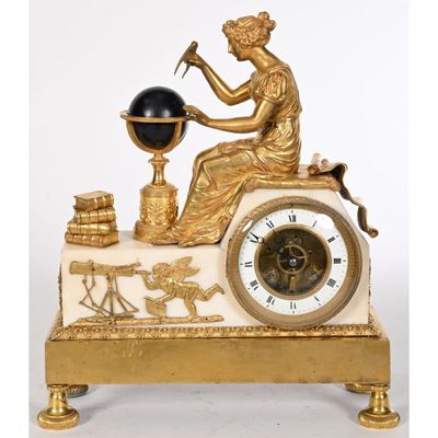 une horloge dorée et blanche représentant une femme tenant un globe terrestre