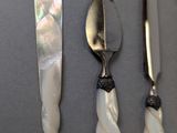 three pieces of silverware with mother of pearl in them on a table