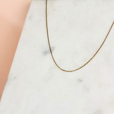 une dalle de marbre blanc sur laquelle est posée une chaîne en or