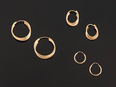 five pairs of gold hoop earrings on a black surface