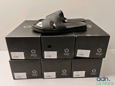 Plusieurs boîtes de chaussures noires sont empilées les unes sur les autres