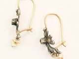 pair of gold and silver earrings with pearls on them on a white surface
