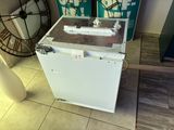 a white refrigerator sitting on a tiled floor next to a fan