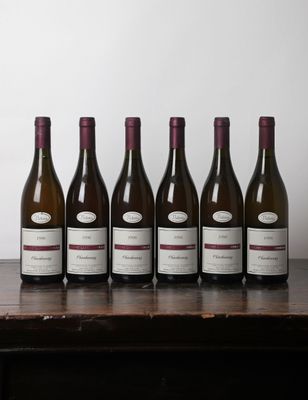 six bottles of wine are lined up on a wooden table