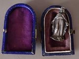 an image of a silver statue of the virgin mary in a purple box