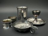 plusieurs plats et tasses en argent posés sur une table devant un fond noir