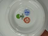 a white plate with a green leaf and a red flower on it