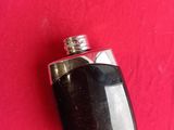 a black flask with a silver top on a red background