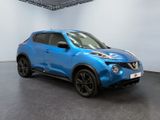 the blue nissan juke suv is parked in a showroom