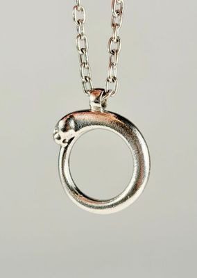 un gros plan d'un collier en argent avec un pendentif circulaire suspendu à une chaîne