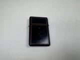 a black lighter sitting on a white surface