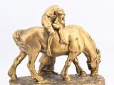 gold figurine of a man riding a horse with a woman on his back