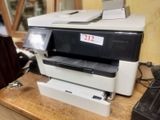 a printer sitting on top of a wooden desk next to a phone