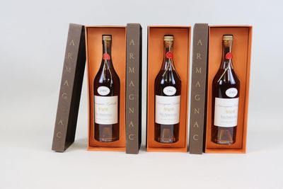 three bottles of wine in a wooden box on a white surface