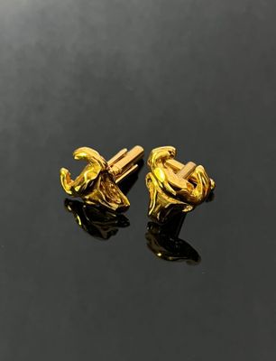 two pairs of gold plated cufflinks on a black surface