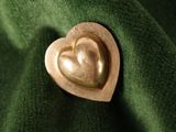 a gold heart shaped brooch on a green cloth