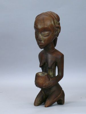 une petite statue en bois représentant une femme tenant un bol