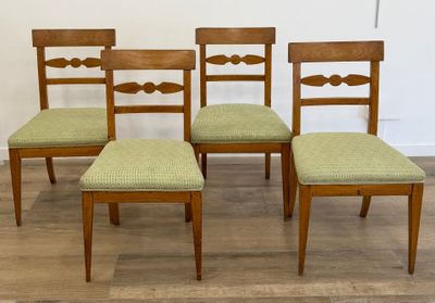 quatre chaises en bois, dont les assises sont recouvertes de tissu vert, sont posées sur un parquet