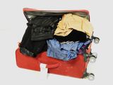 une valise rouge remplie de vêtements et un sac noir