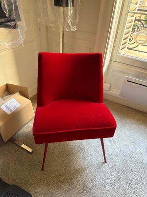 une chaise rouge dans une pièce où se trouve une boîte par terre