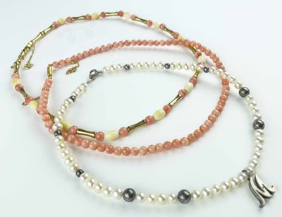 three necklaces with different colored beads on a white surface