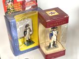 three toy soldiers in boxes on a table