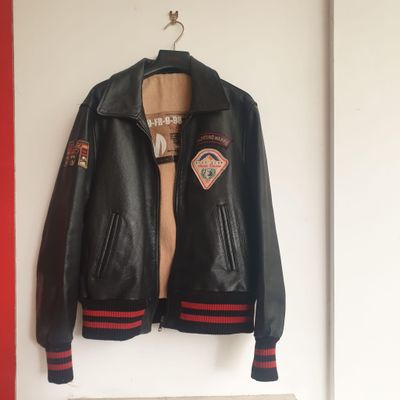 une veste en cuir noir accrochée au mur, près d'un radiateur