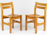 two wooden chairs sitting next to each other on a white surface