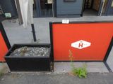 un mur rouge sur lequel sont posés une jardinière noire et une pancarte