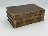 trois vieux livres empilés sur une surface blanche