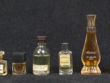 bottles of different types and sizes of perfumes lined up on a black surface
