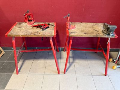 deux tables rouges sur lesquelles sont posés des outils, dans une pièce