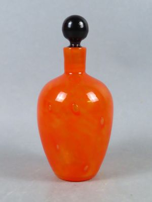 une bouteille en verre orange avec un bouchon noir, posée sur une surface blanche