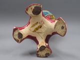 une figurine en céramique représentant une croix sur laquelle est perché un oiseau