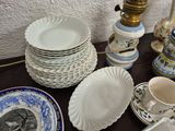 many plates and cups on the table next to a lamp
