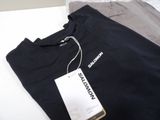 a black t - shirt with a tag on it sitting on a bed