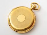 an image of a gold pocket watch on a white surface