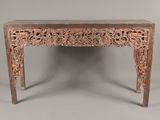 une vieille table en bois dont le plateau est orné de sculptures
