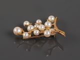 pearl and gold broochle with leaves on a black surface