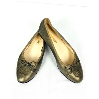 une paire de chaussures pour femme en or, ornées de nœuds, posées sur un fond blanc