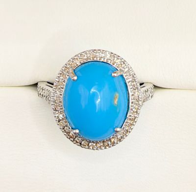 a close up of a ring with a blue stone surrounded by diamonds