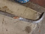 une vieille crosse de hockey posée par terre à côté d'une canette de soda
