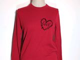 Le pull est rouge et il y a un cœur noir dessus.