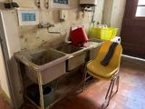 une cuisine sale avec un évier et une chaise jaune