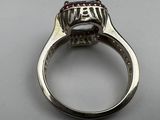 a close up of a silver ring with a red stone in it