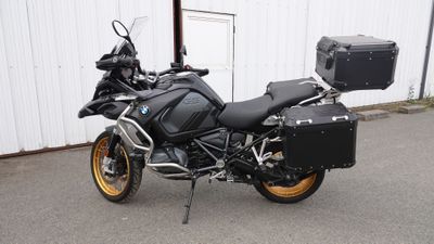 Une moto BMW garée devant un immeuble, avec une valise à l'arrière